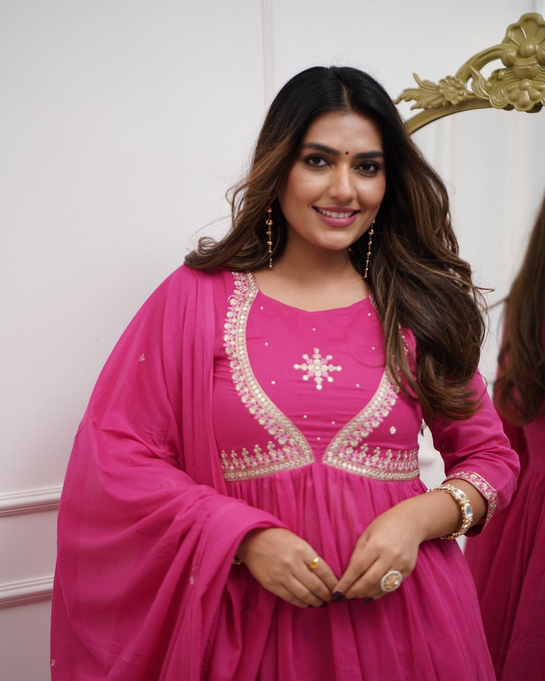 Close-up of a woman smiling, wearing a pink Muslin Cotton embroidered kurta set with a matching dupatta, showcasing delicate neckline work.