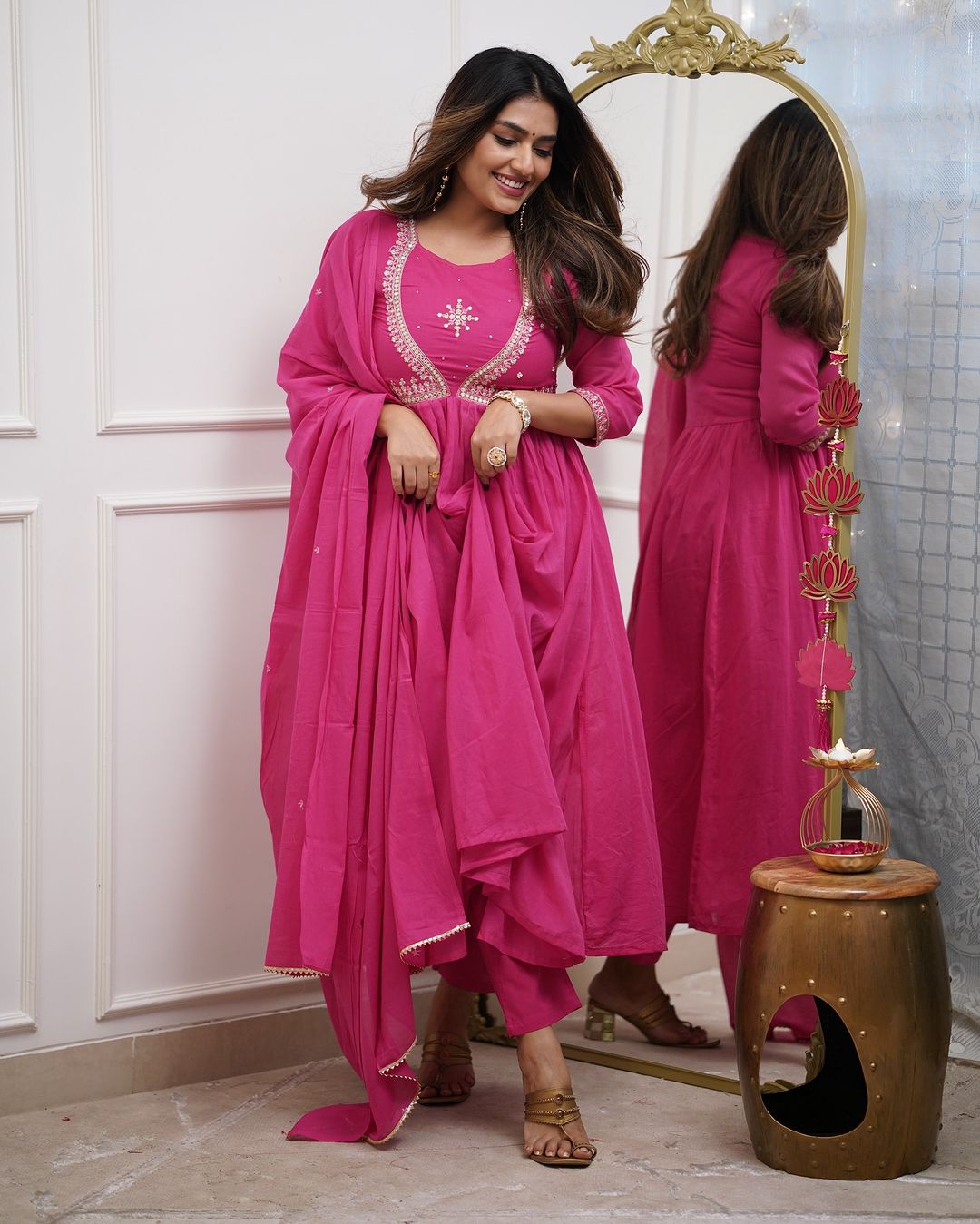 Woman in a pink embroidered Muslin Cotton kurta set, playfully showing the flow of the flared kurta and pant details.
