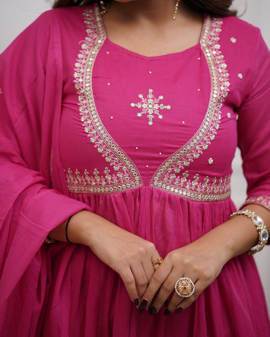 Detailed close-up of the intricate embroidery and mirror work on the neckline of the pink Muslin Cotton kurta, with hands showing accessories.