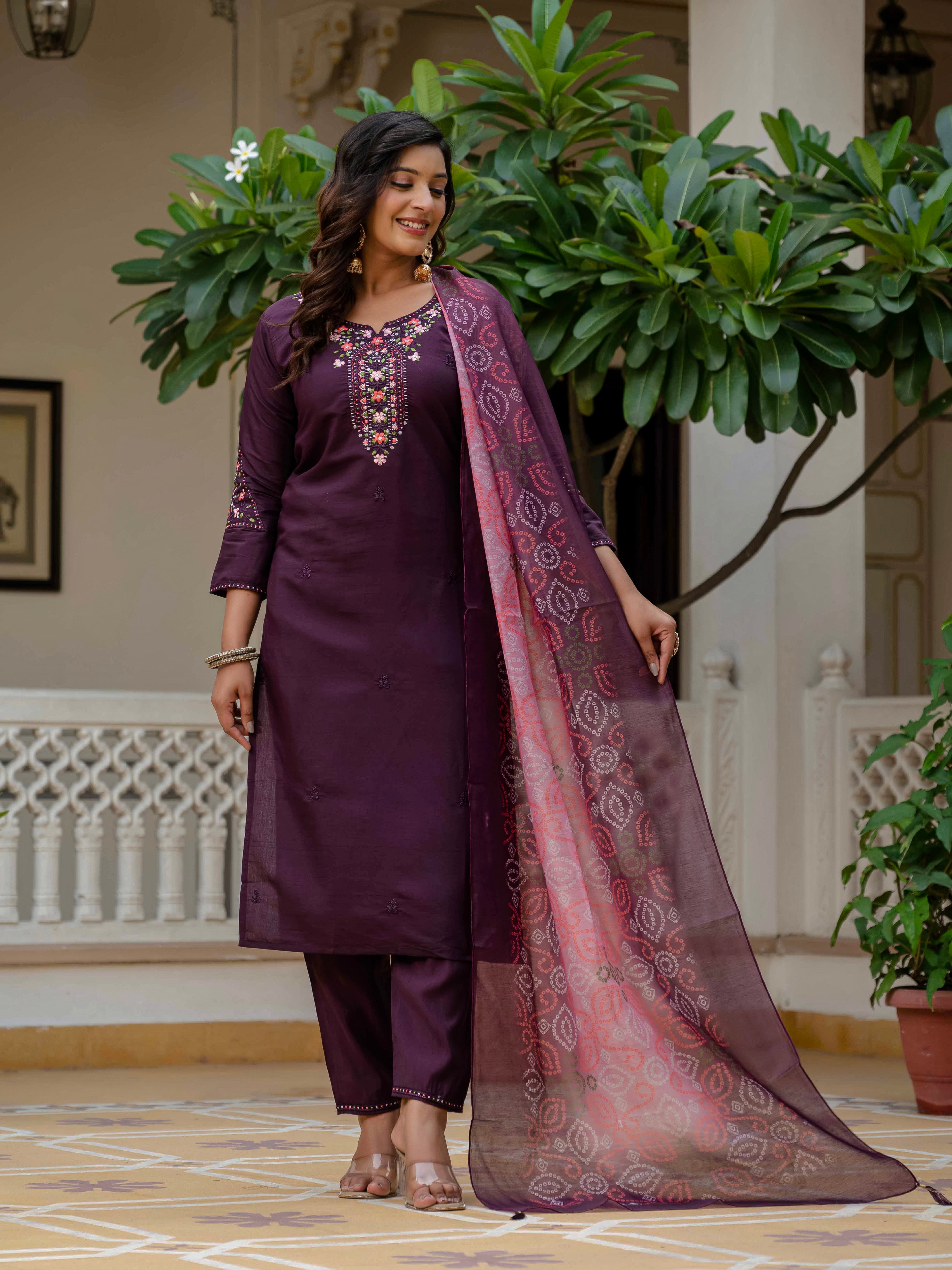 Smiling woman in a stylish plum Roman silk kurti set featuring intricate embroidery and a vibrant muslin bandhani dupatta.