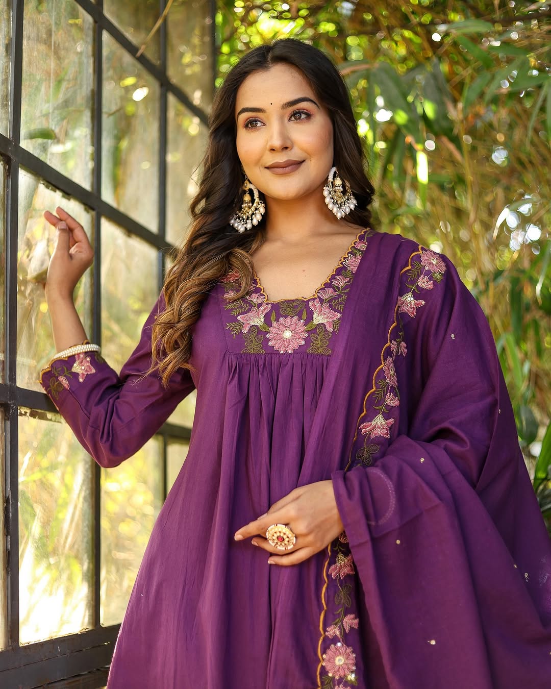 Model in purple rayon slub kurti set with embroidered neckline and chanderi dupatta, looking out a window thoughtfully.