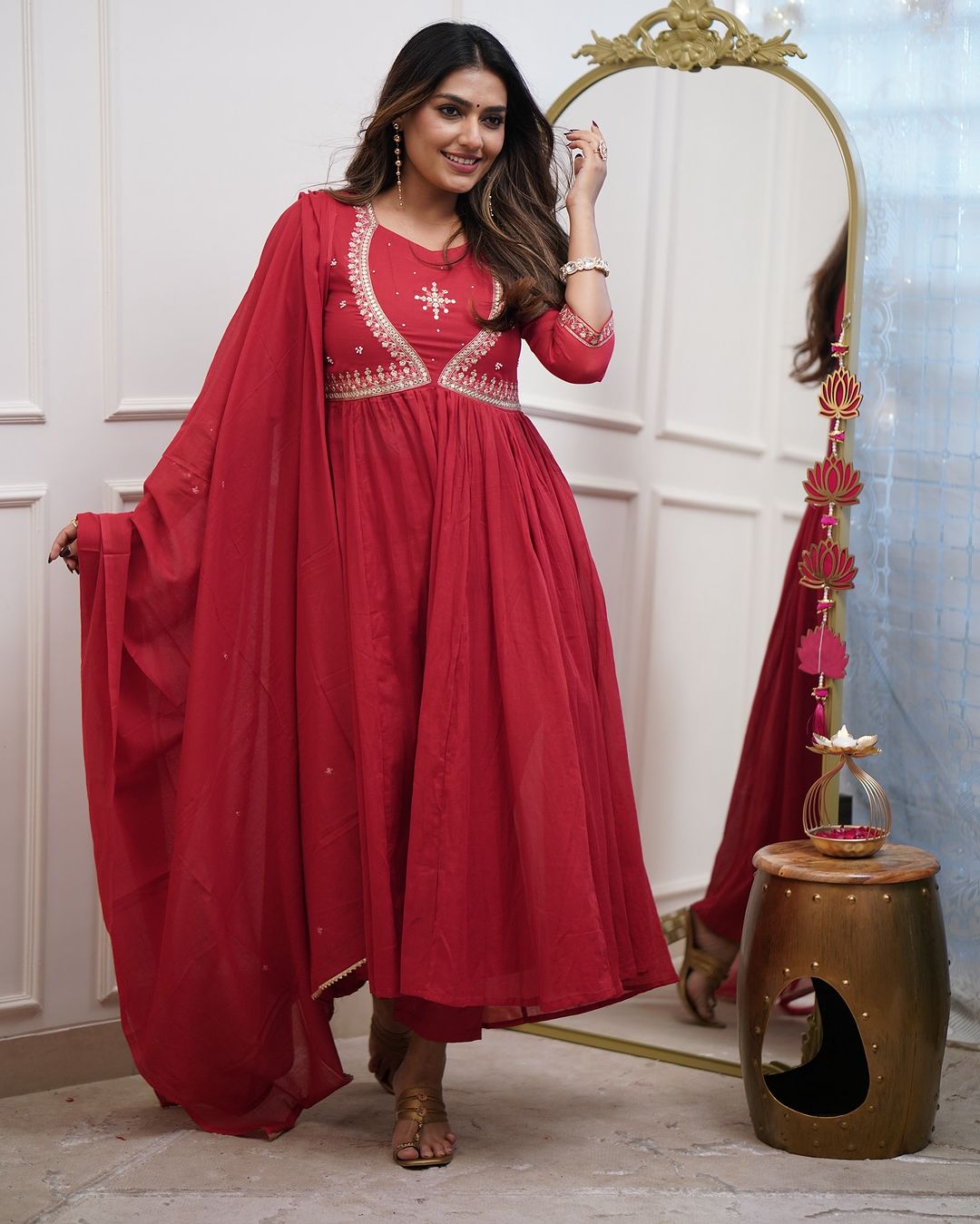 Full shot of a woman in a rich red Muslin Cotton kurta set with pant and dupatta, standing stylishly next to a mirror.