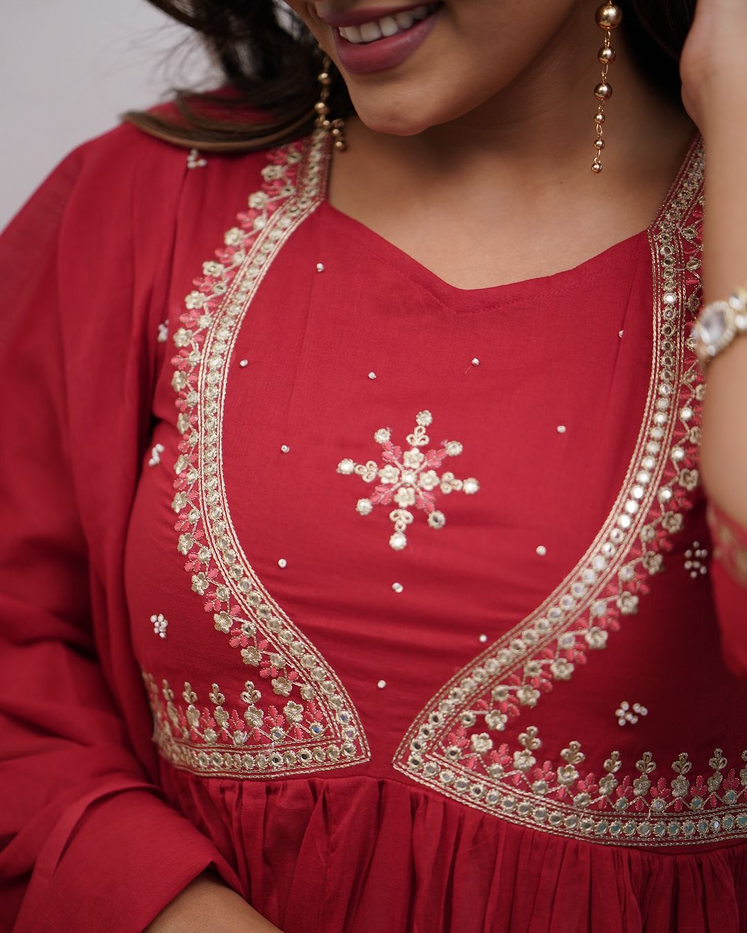 Detailed close-up of the elegant embroidery and mirror work on the neckline of the red Muslin Cotton kurta.