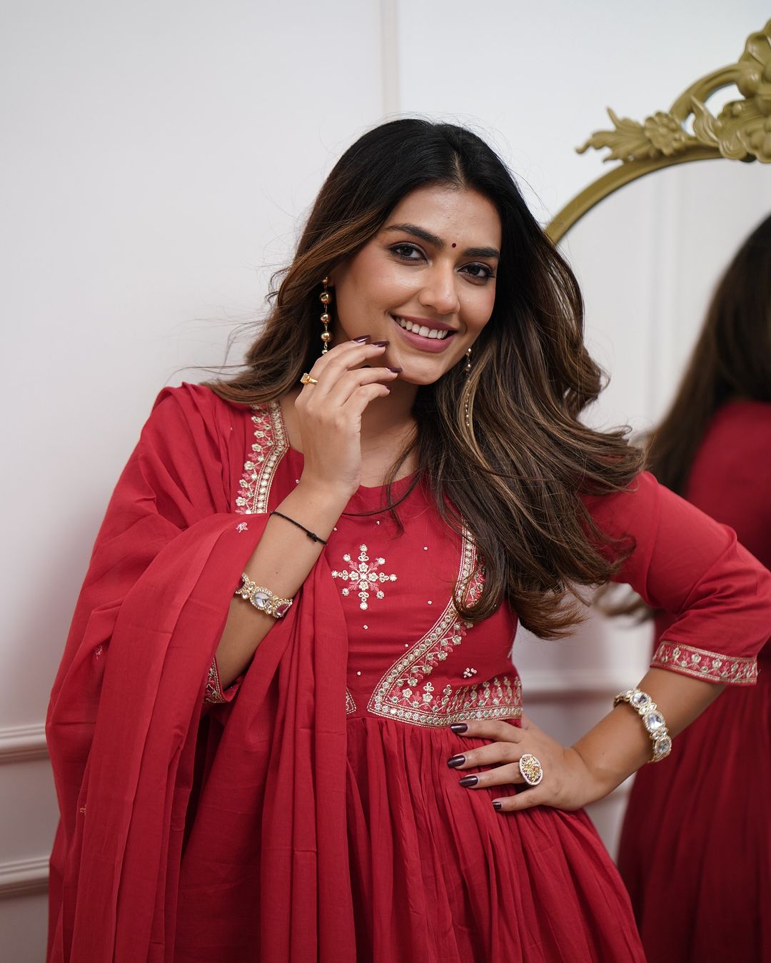 Woman in a red Muslin Cotton kurta set, posing confidently with a hand on her hip, highlighting the set's festive appeal and detailed embroidery.
