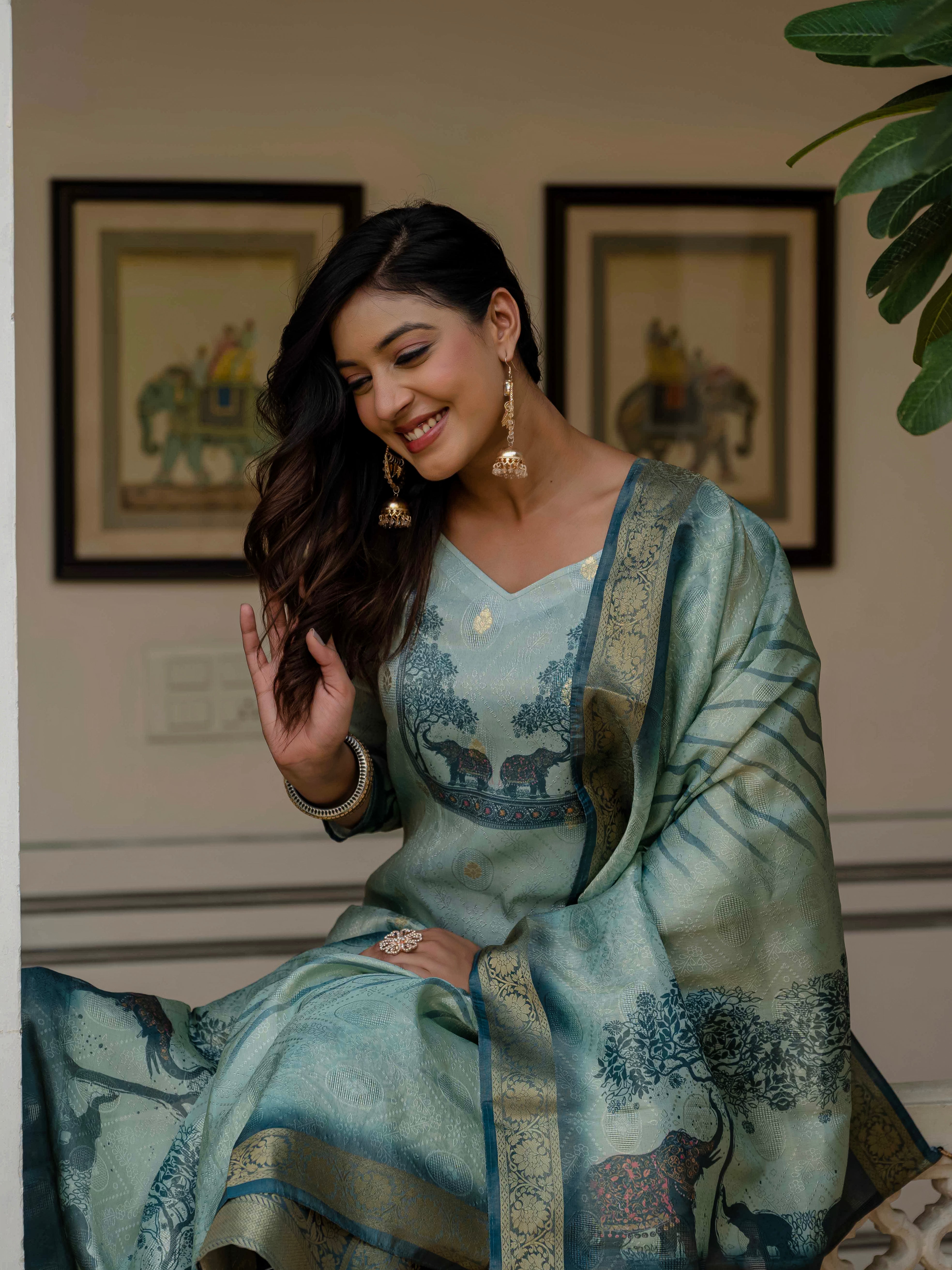 Smiling woman in Royal Blue kurta set, looking down thoughtfully, showcasing detailed earrings.