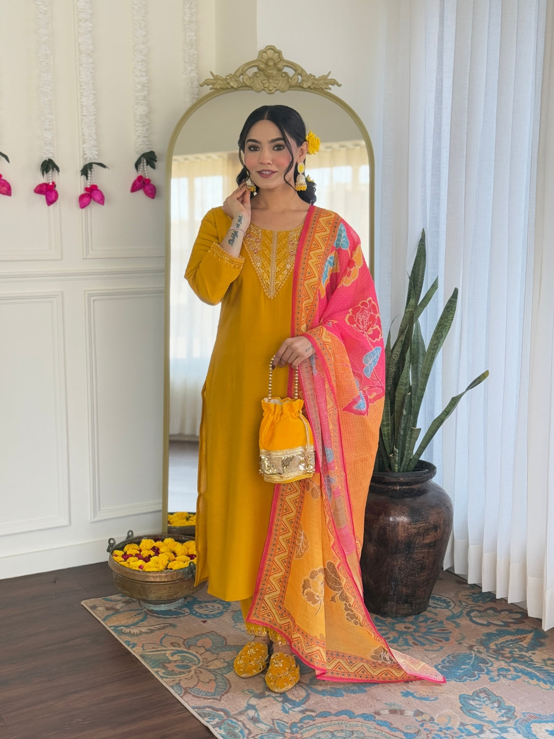 TRENDBUY model showcasing VI-Rose Mustard Yellow Chanderi Silk Kurti Set with embroidered neckline and vibrant pink-orange printed linen dupatta, holding a matching potli bag.
