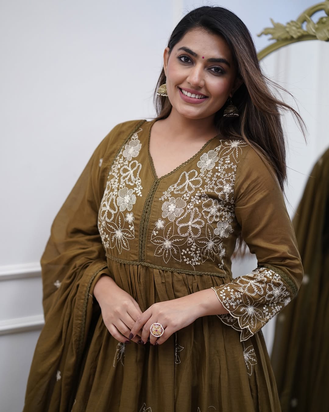 Cheerful model in TRENDBUY Sapna olive green cotton silk gown, featuring the white embroidered design on the chest and sleeves.