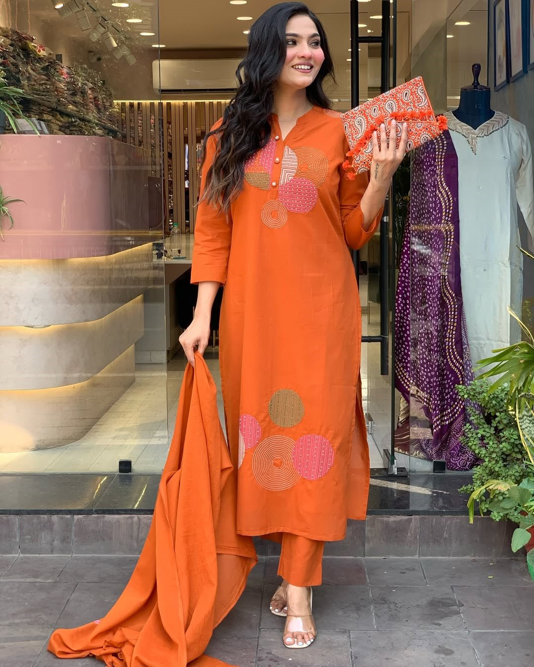 Stylish model in TRENDBUY ST-KASHMIRA orange kurti set, holding an embroidered clutch bag