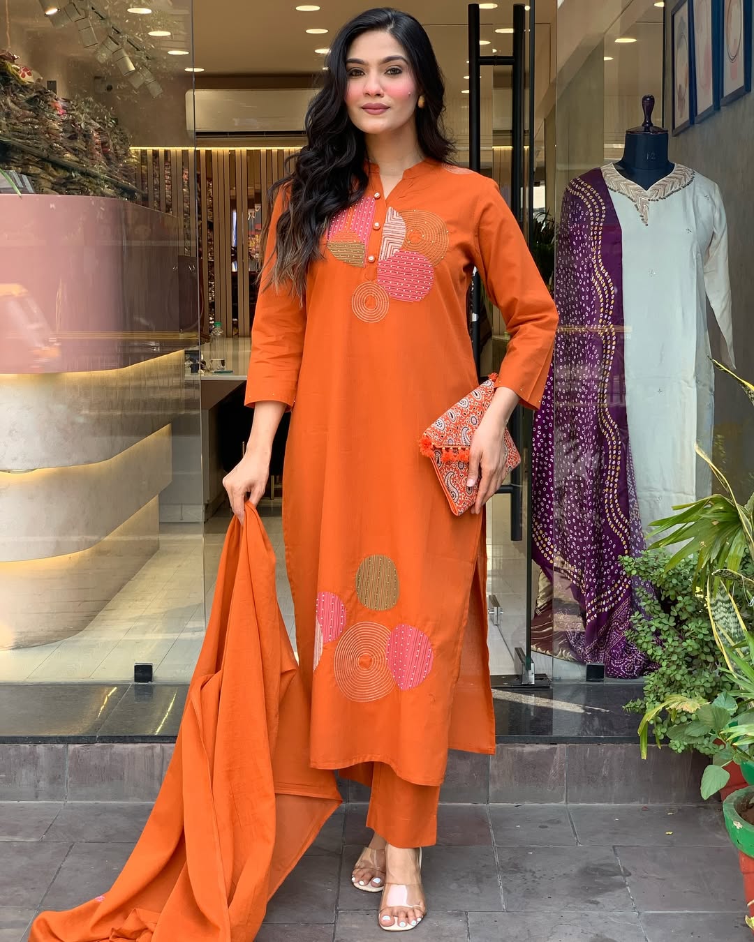 Model confidently posing in TRENDBUY ST-KASHMIRA orange ethnic wear, showing side slits
