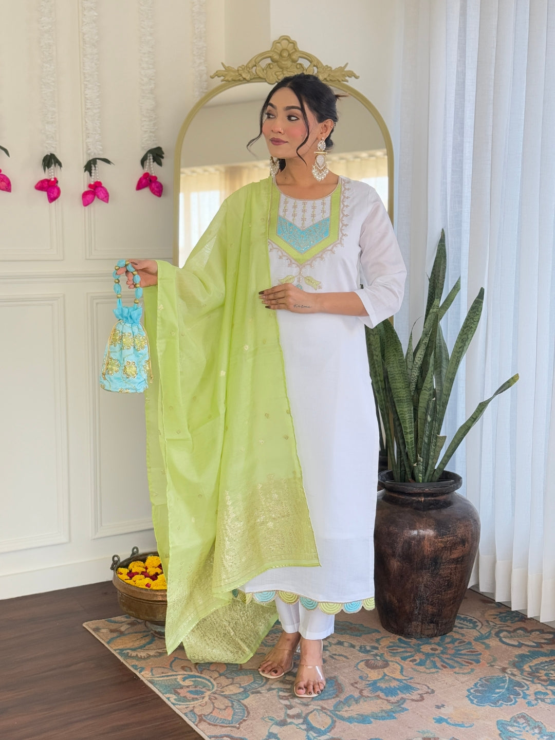 Model posing in white Viscose Chanderi kurta set with light green embroidered dupatta and potli bag, front view.