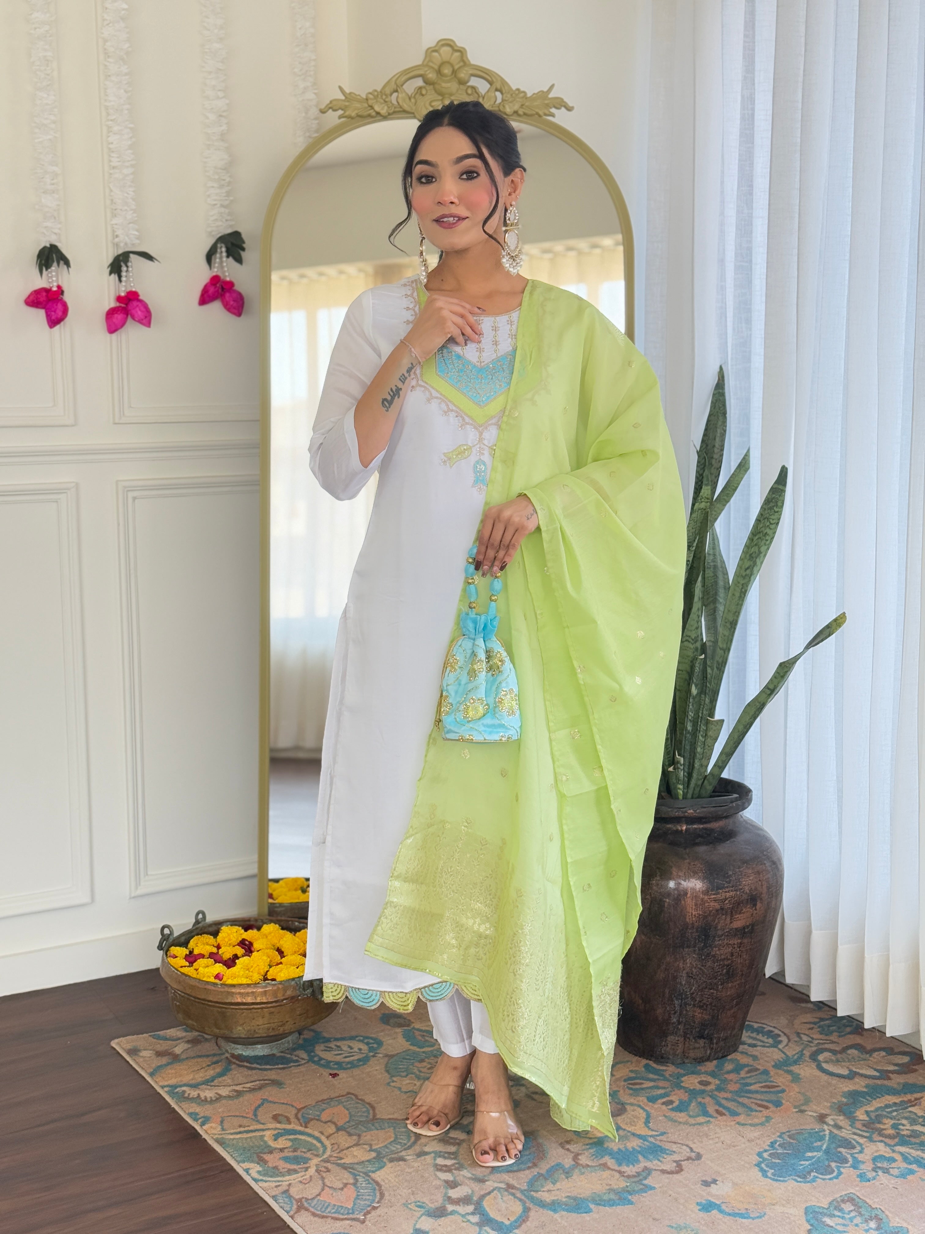 Front-facing view of the model with the white kurta set and lime green dupatta, hand on chest.