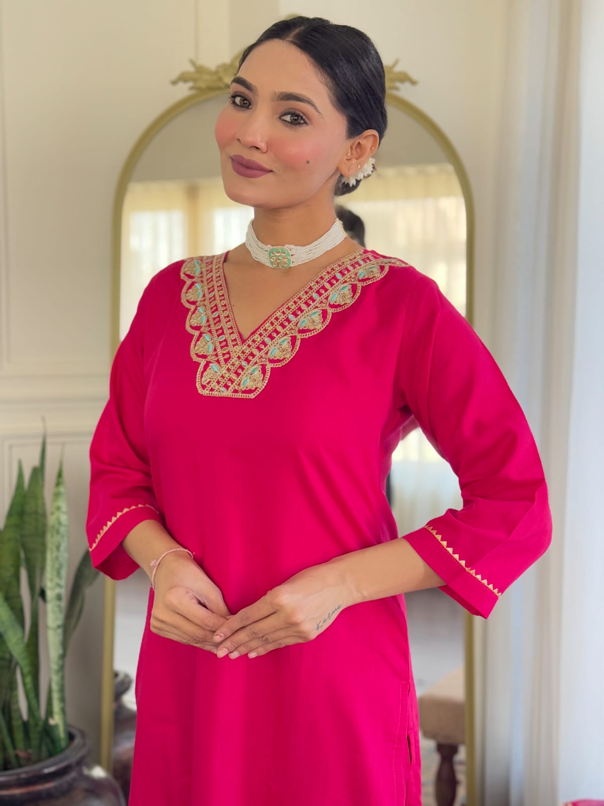 Close-up of the model's upper body, featuring the intricate golden embroidery and turquoise accents on the V-neck of the hot pink rayon kurti.