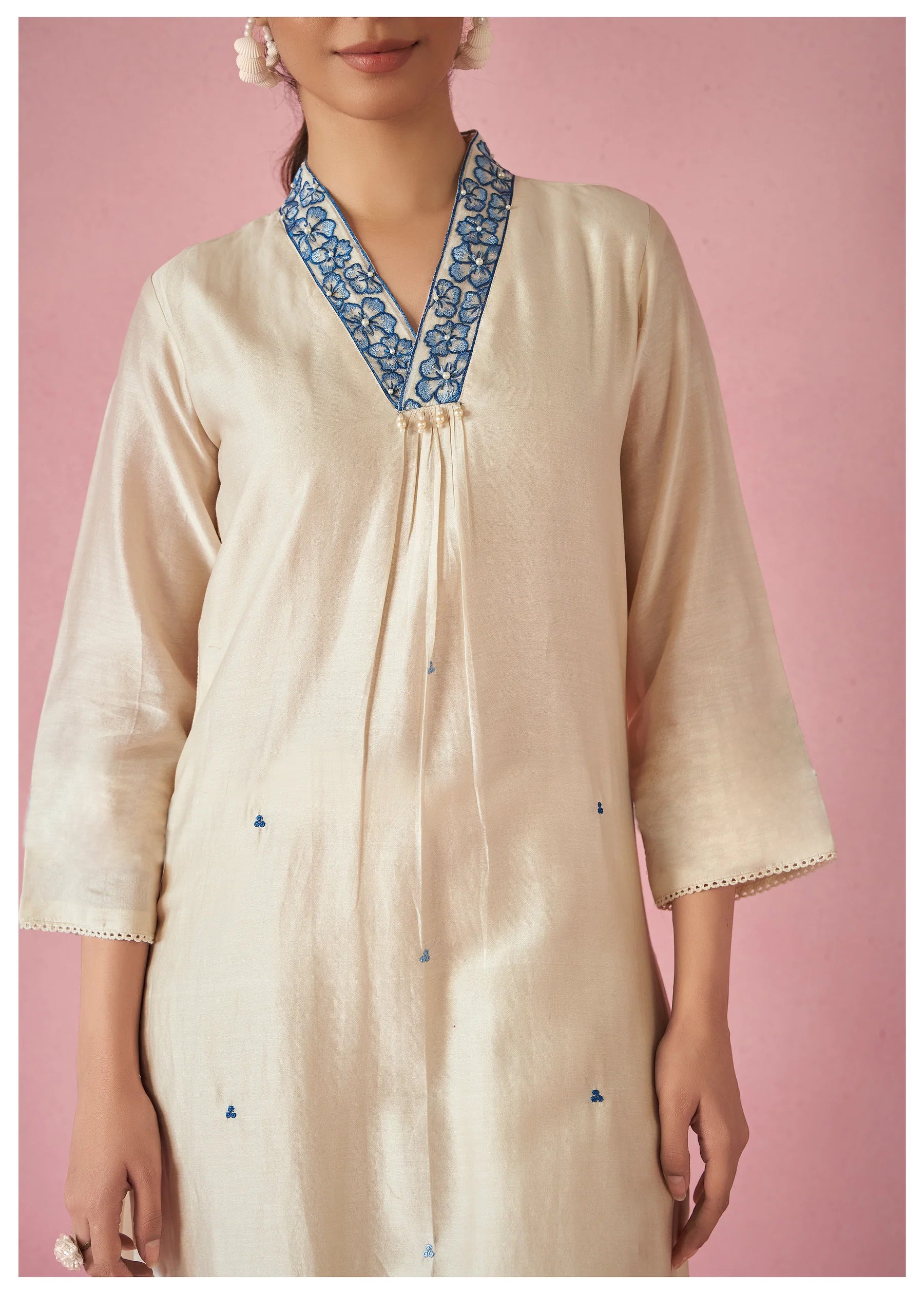 Close-up of the TRENDBUY white kurti's V-neckline with delicate blue floral embroidery and detail on the three-quarter sleeves, highlighting craftsmanship.
