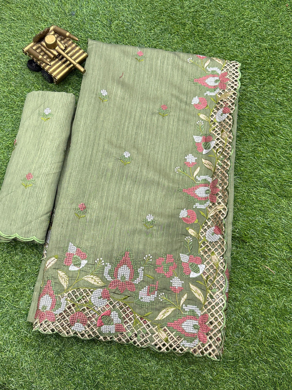 Close-up of the delicate thread embroidery and intricate cutwork border on the light green silk fabric