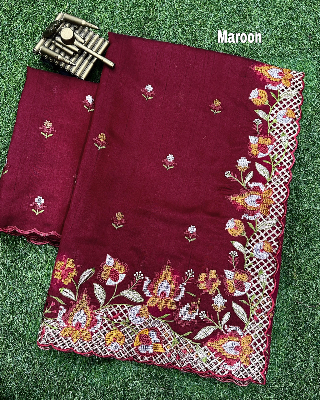 Close-up of the intricate floral thread embroidery and delicate cutwork border on rich maroon fabric
