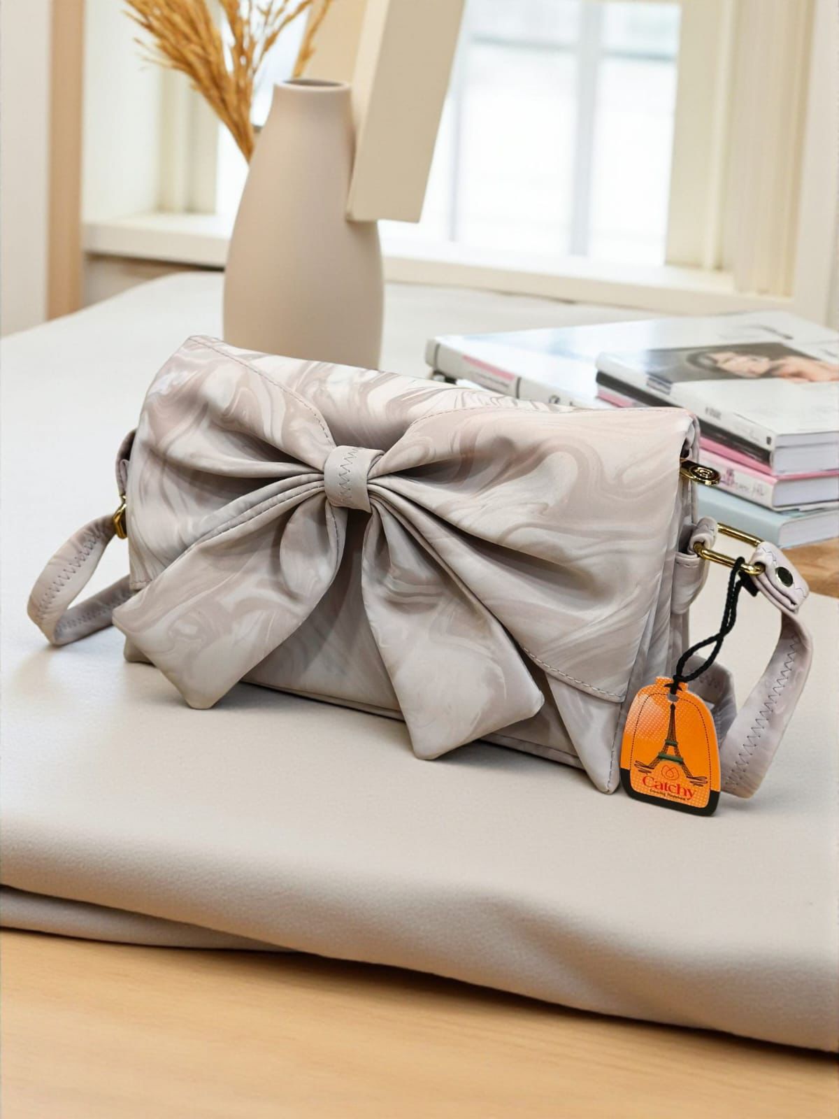 A sophisticated cream-colored marbled velvet bag with a sculpted bow detail