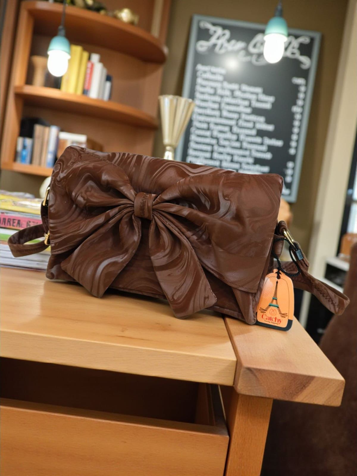 The Catchy crossbody bag in brown marbled velvet with a large statement bow.