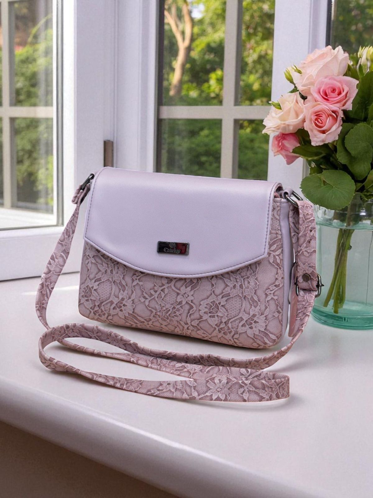 White and pink lace handbag on a windowsill with a vase of flowers.