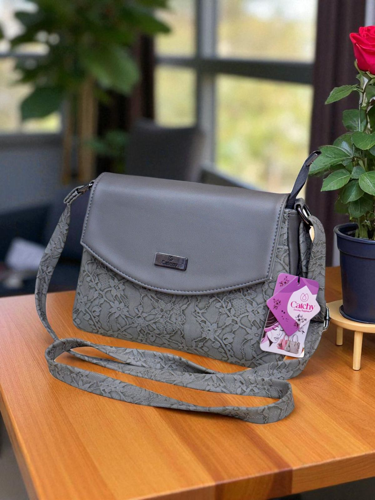 Gray lace handbag on a wooden table with a blurred indoor background