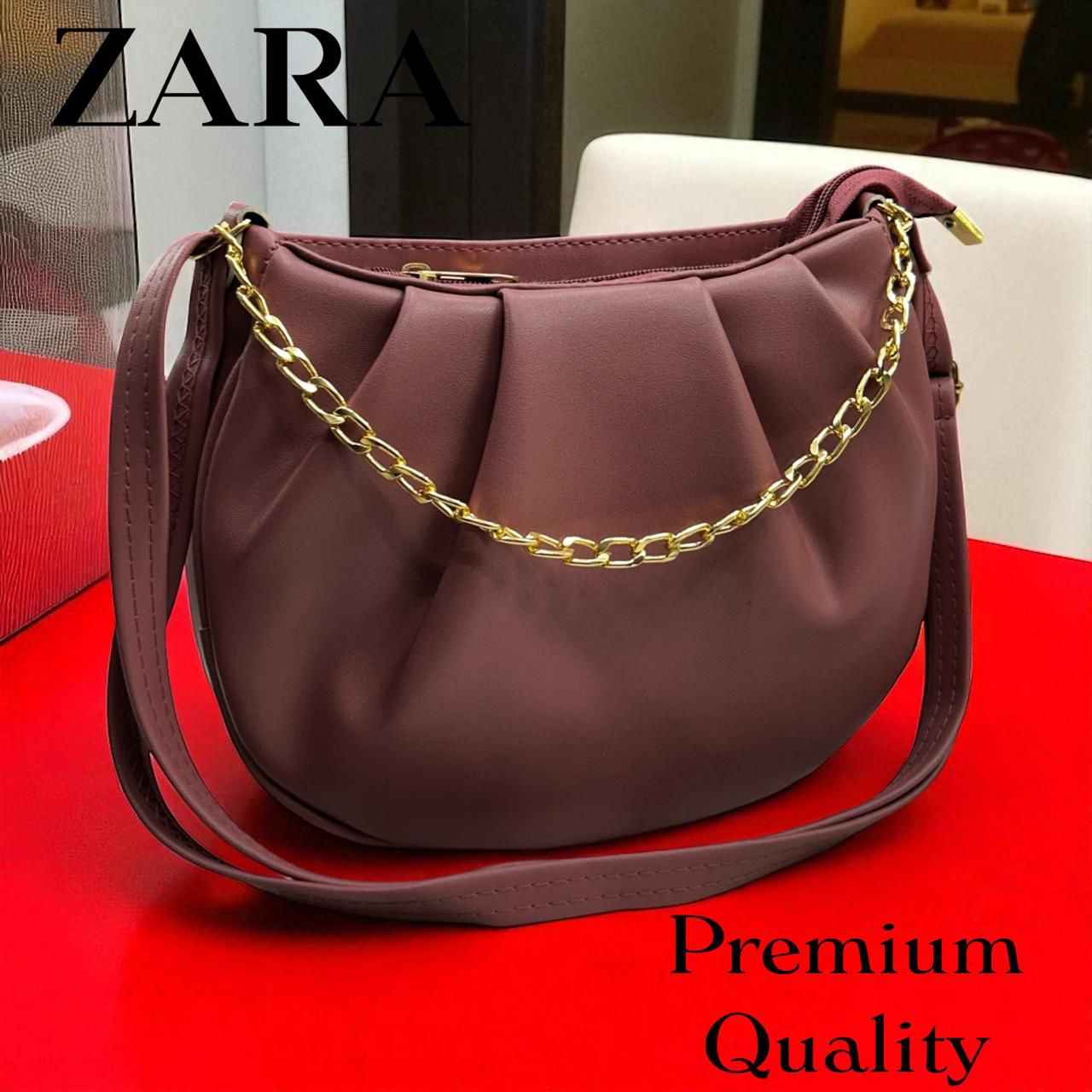 Purple handbag with gold chain on a red surface, Zara brand visible
