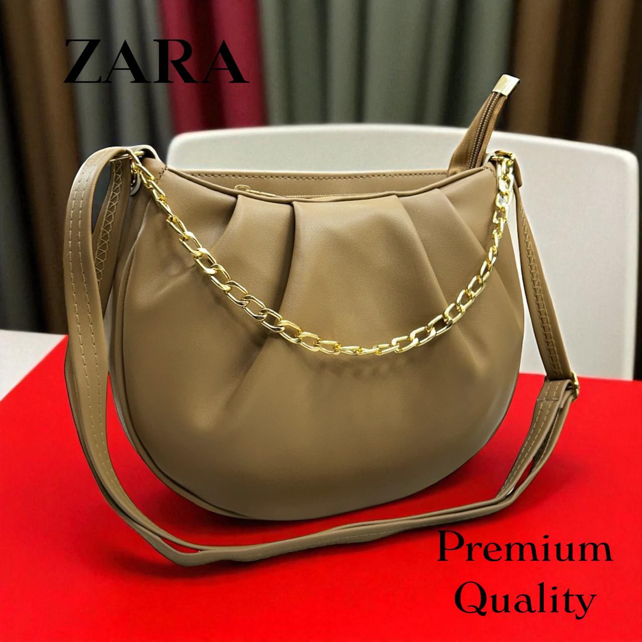 Beige handbag with gold chain on a red surface, Zara brand visible