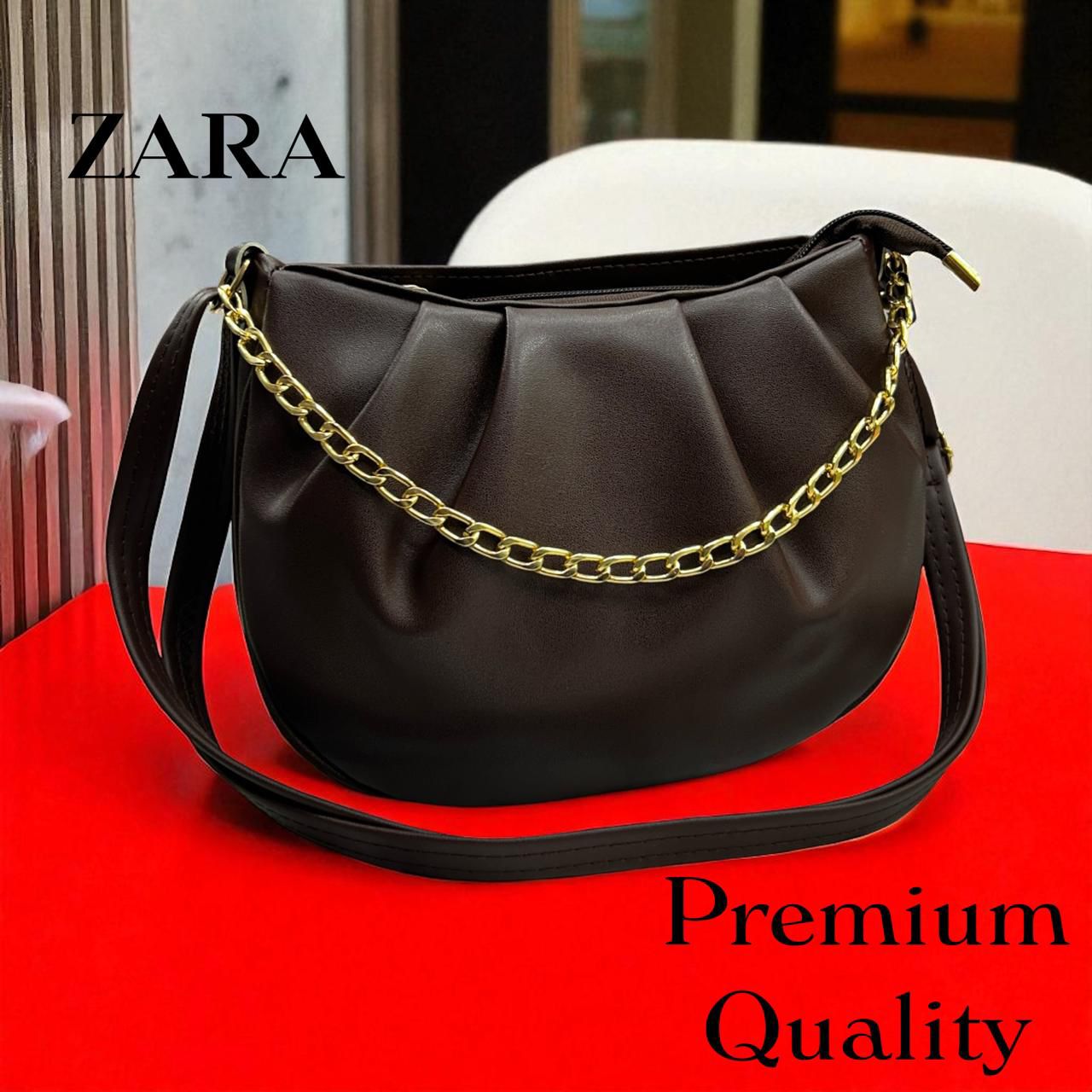 Black handbag with gold chain on a red surface, Zara brand visible