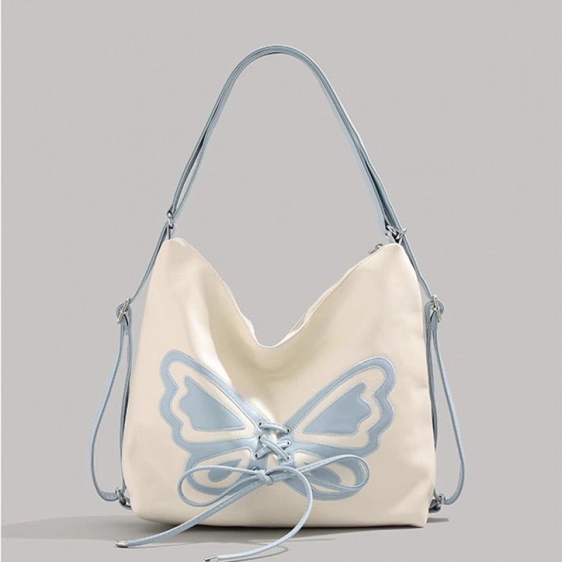Beige handbag with blue butterfly design on a gray background