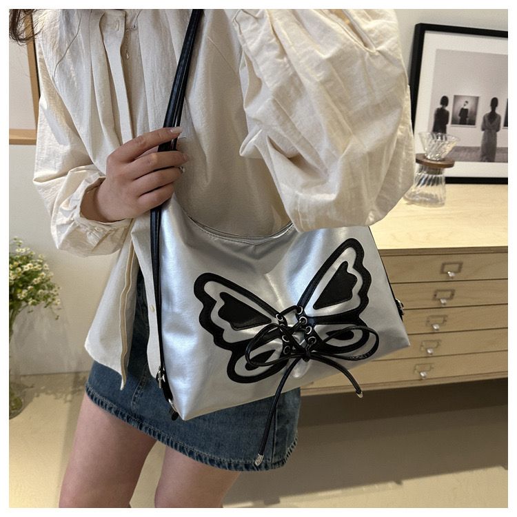 Model wearing the silver butterfly bag converted into a backpack.
