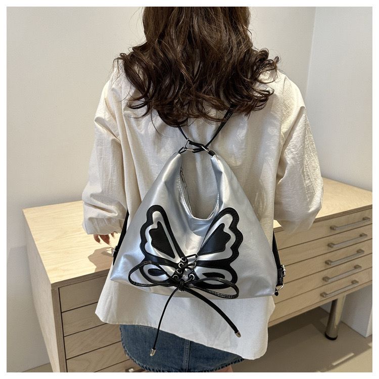Model wearing the silver butterfly bag converted into a backpack.