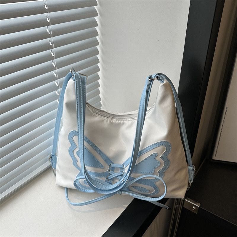 A chic white shoulder bag featuring a light blue butterfly design with corset lacing