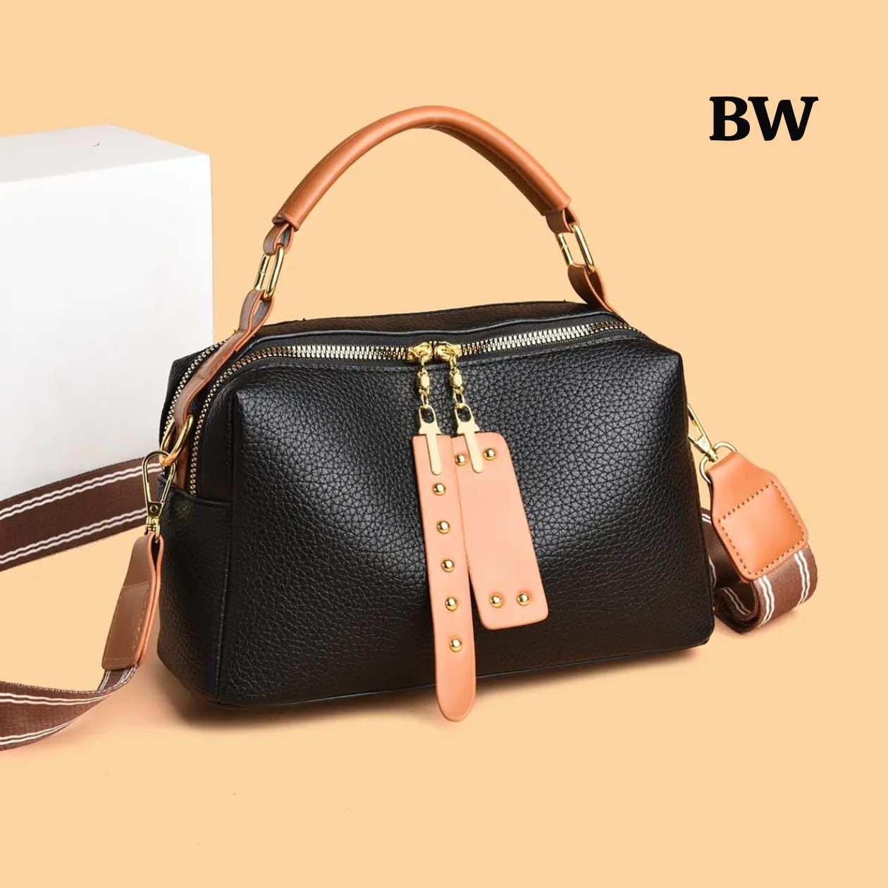 Black handbag with brown handle and strap on a beige background