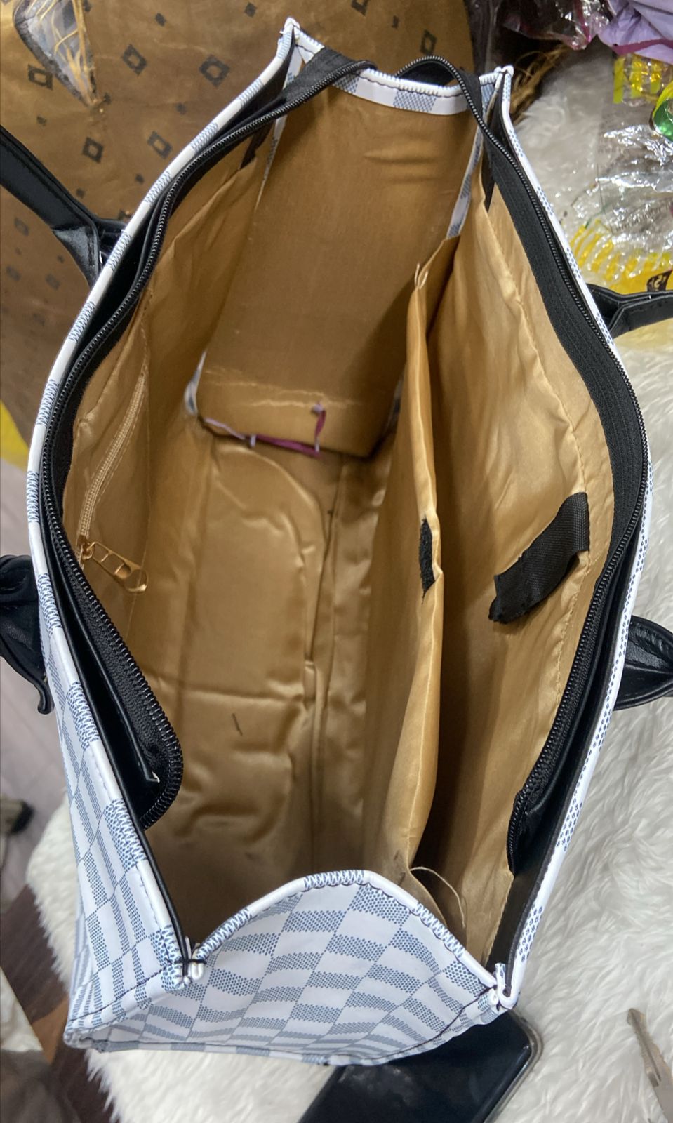 Overhead view of the organized interior of a white checkered tote bag showing multiple compartments and zippered pockets, emphasizing its practicality.