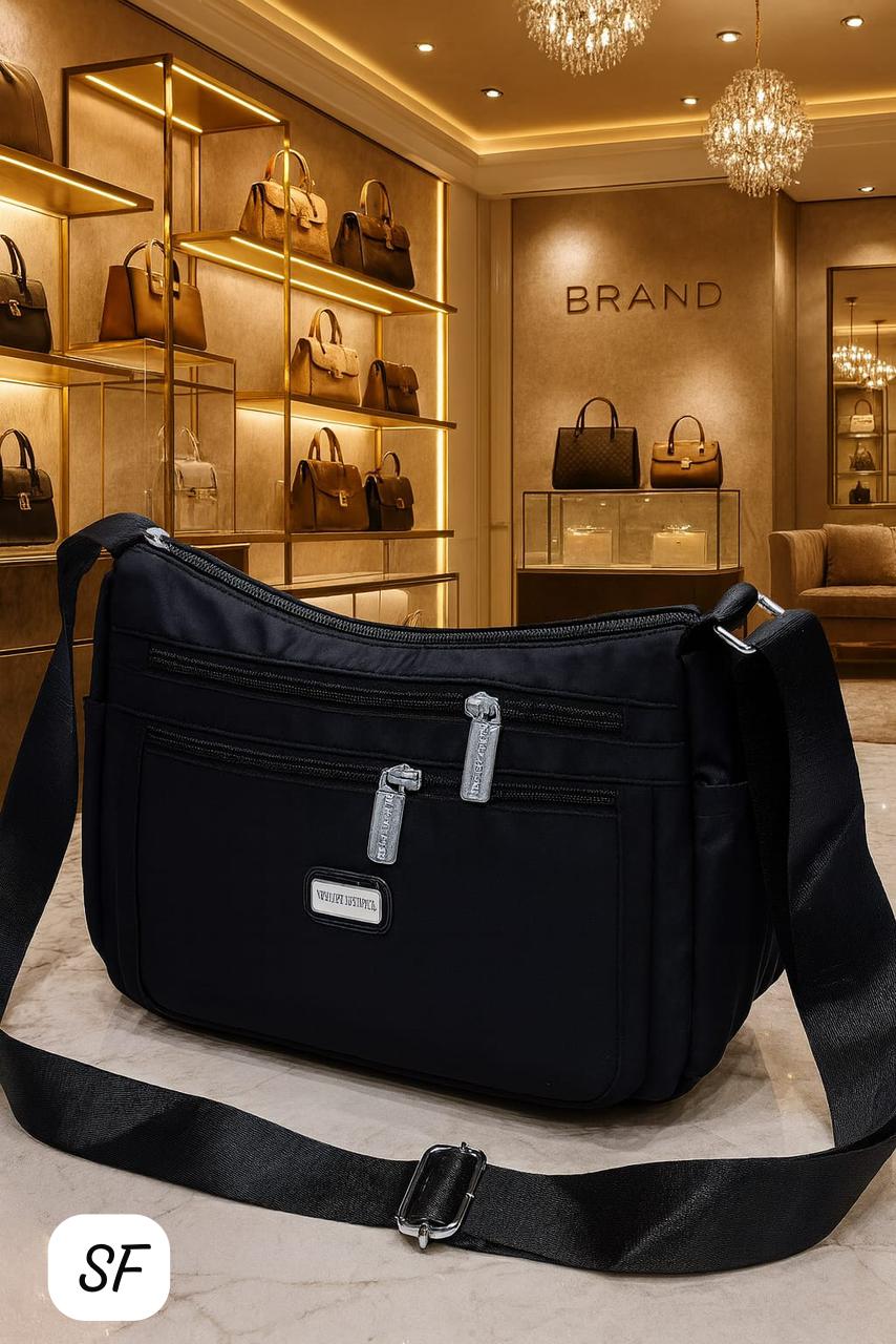 TRENDBUY sophisticated black multi-zip sling bag with adjustable strap in an elegant retail setting