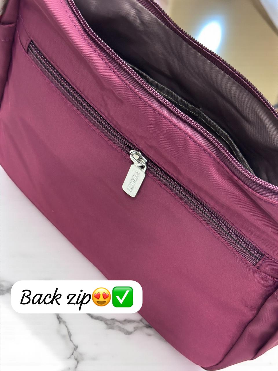 Detail shot of the secure back zip pocket on TRENDBUY's premium maroon sling bag with silver hardware