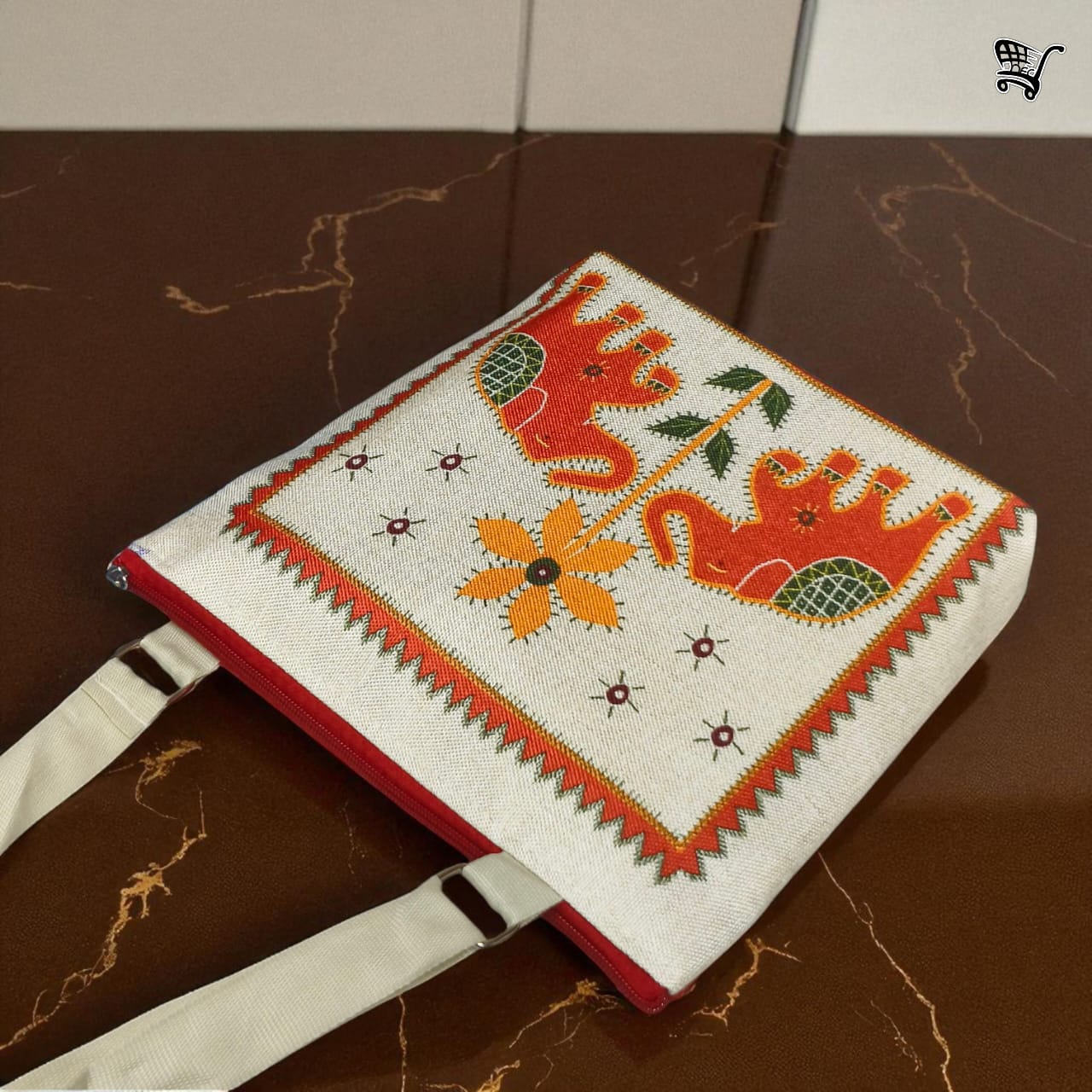 Close-up of TRENDBUY red elephant print jute sling bag, highlighting the intricate print and border detail on a marble surface.