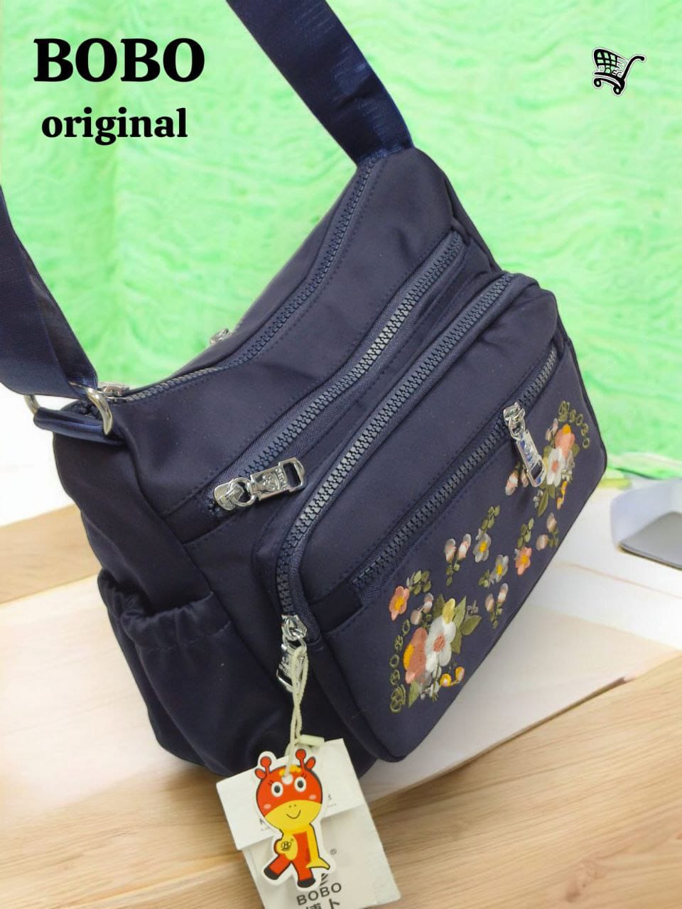 Side view of TRENDBUY BOBO Original navy blue floral crossbody bag on a wooden surface