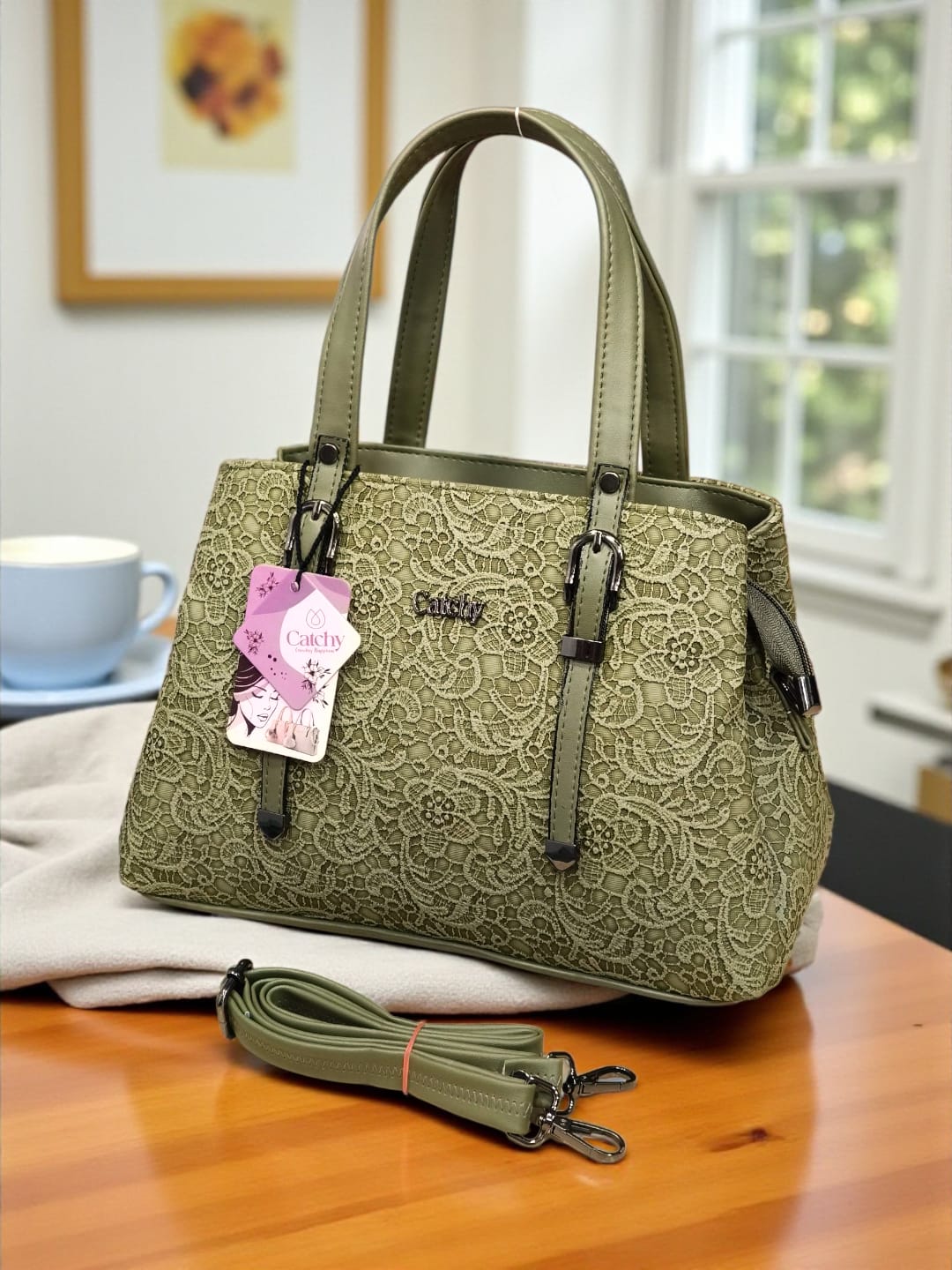 Chic olive green floral embossed TRENDBUY handbag with matching adjustable strap, presented on a wooden table in a cozy interior.