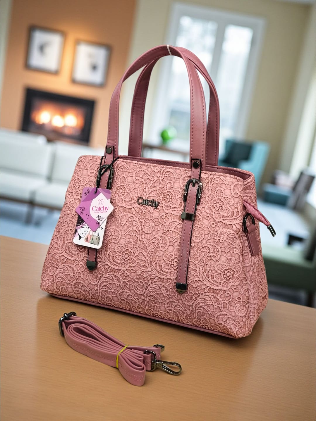 Beautiful dusty rose pink floral embossed TRENDBUY handbag, complete with a versatile sling strap, set against a cozy home interior with a fireplace.