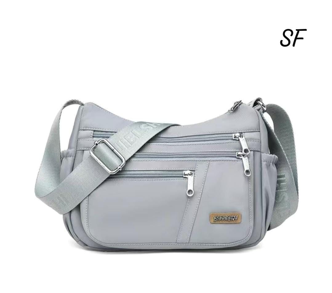 TRENDBUY Light Grey Premium Imported Sling Bag with multiple front zippers and adjustable strap on a white background.
