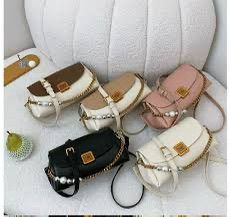 Collection of 5 TRENDBUY Premium Broad Belt PU Slingbags in various colors: Brown/Cream, Tan/Cream, Pink/Blush, Black, and Cream White, featuring gold chain and pearl details on a white textured surface.