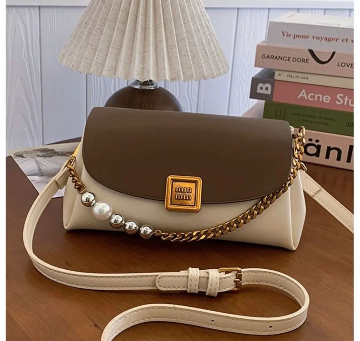 TRENDBUY Premium Broad Belt PU Slingbag in two-tone Brown and Cream, featuring a gold metallic logo, chunky gold chain, and pearl details, with an adjustable cream strap on a wooden table.