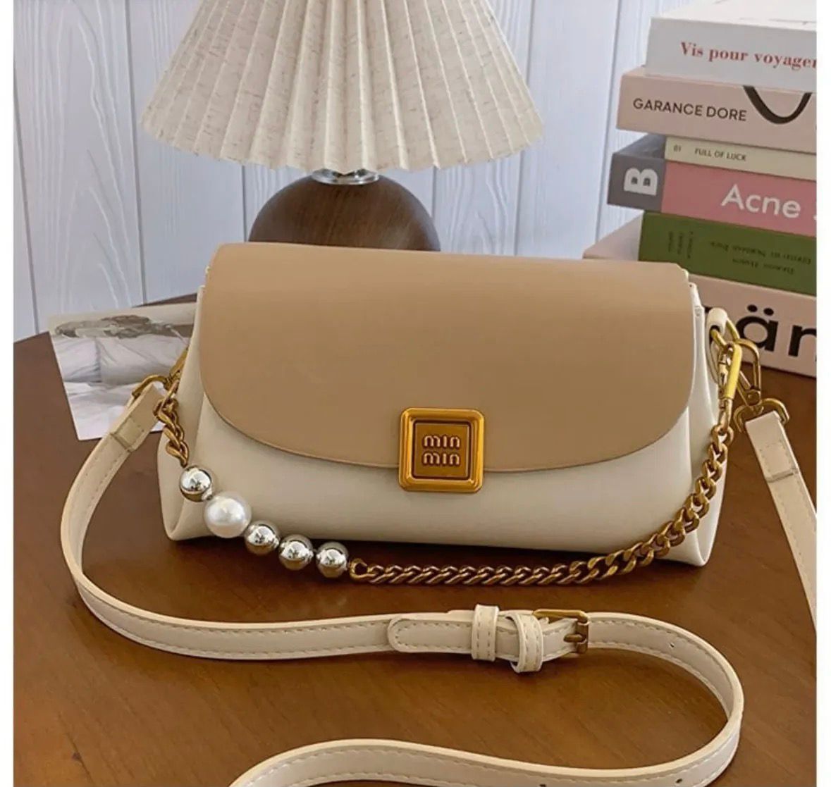 TRENDBUY Premium Broad Belt PU Slingbag in two-tone Tan and Cream, highlighting a prominent gold metallic logo, sophisticated gold chain, and pearl accents, with an adjustable cream strap on a wooden table.