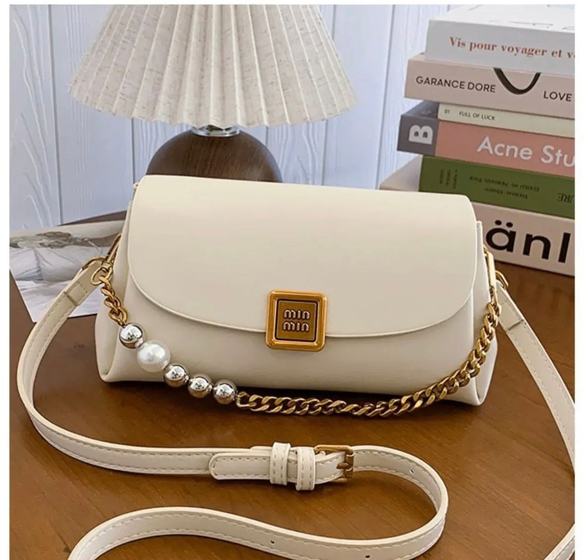 TRENDBUY Premium Broad Belt PU Slingbag in classic Cream White, featuring a gold metallic logo, stylish gold chain, and pearl details, with an adjustable cream strap on a wooden surface.