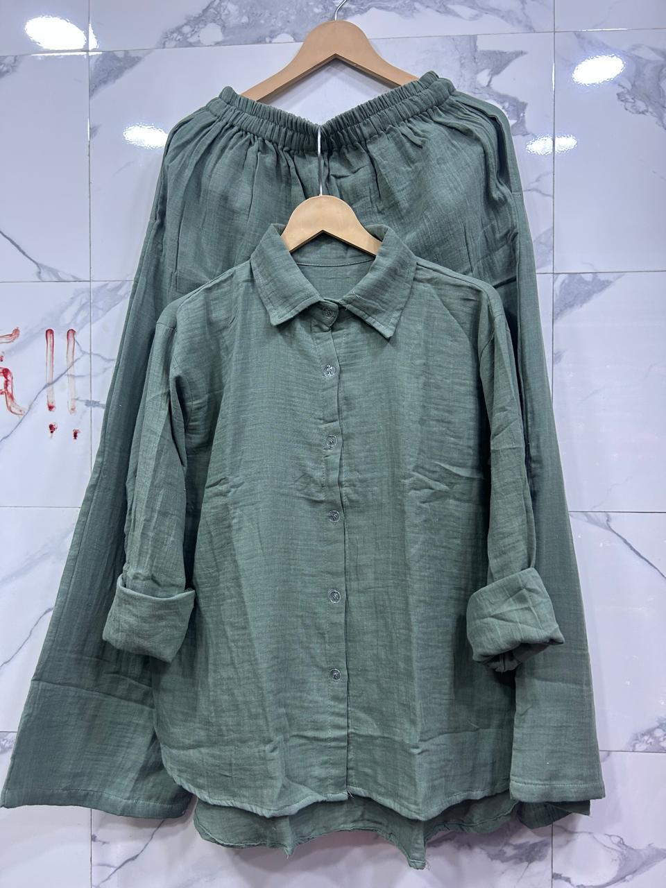 Full view of Olive Green Mul Mul Cotton Cord Set, on a white marble patterned wall with simple hanger.