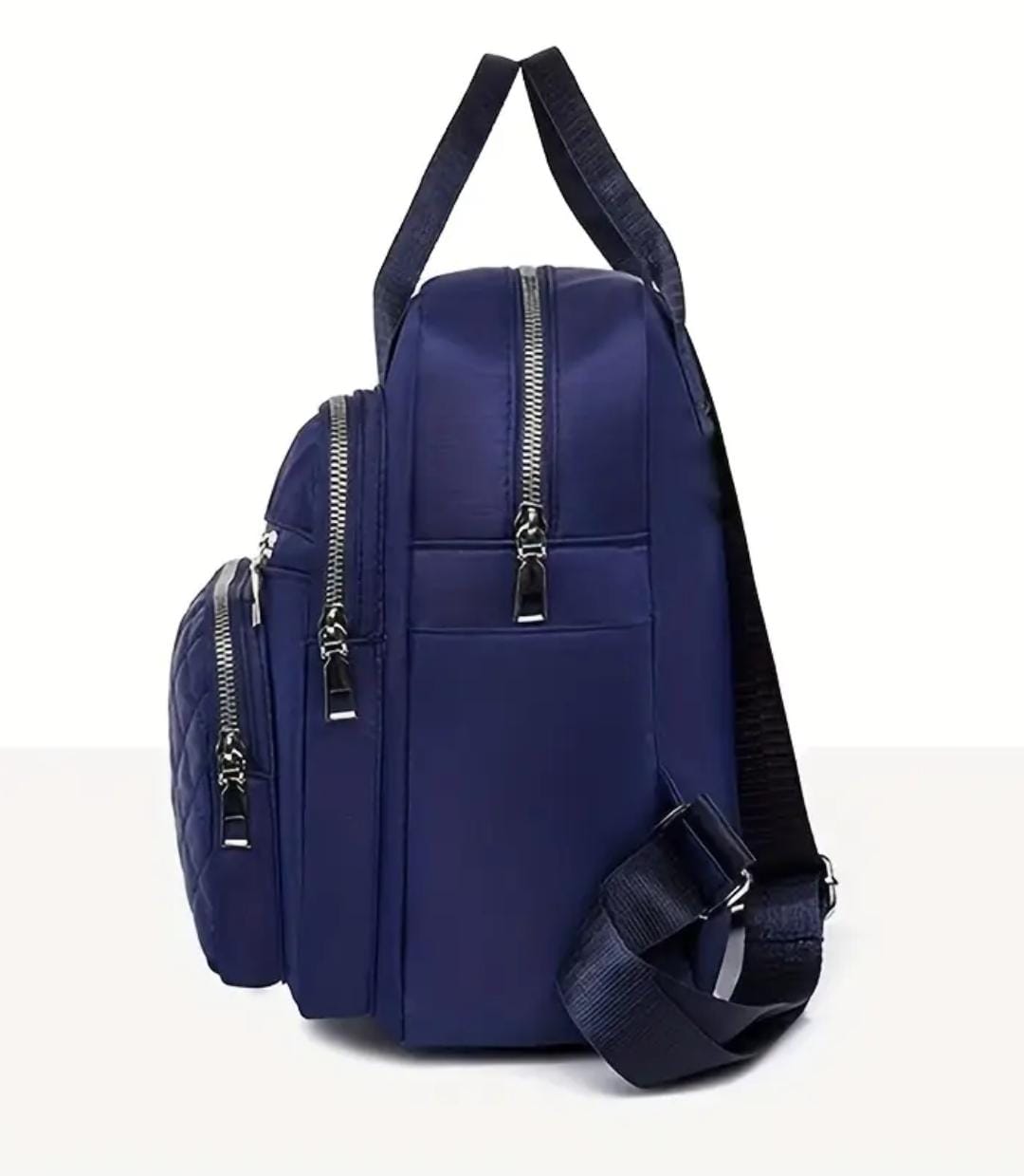 Side profile of the navy blue quilted nylon backpack, revealing multiple zippered pockets and robust construction.
