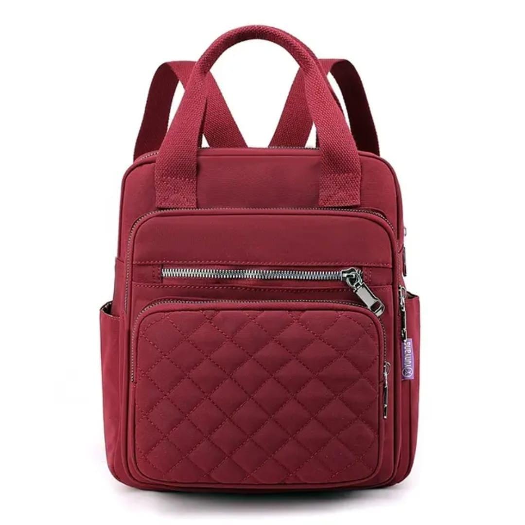 Front view of the red quilted nylon backpack, emphasizing its structured design and visible quilting.