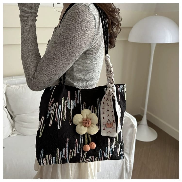 TRENDBUY black floral charm tote bag with braided strap, carried by a woman