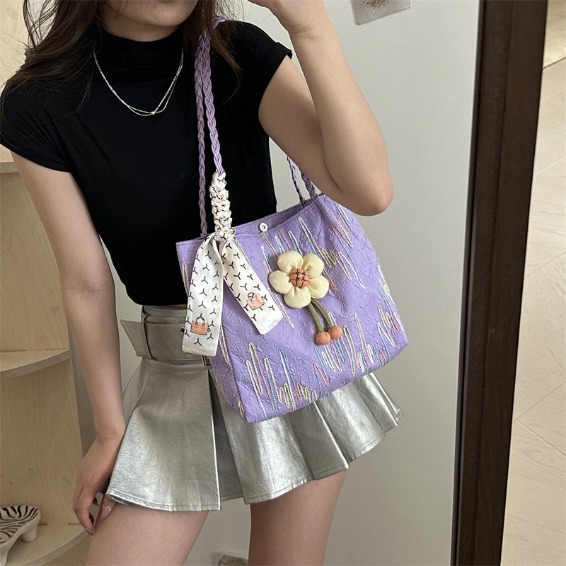 TRENDBUY purple floral charm tote bag with braided strap, worn by a woman in a black top and silver skirt