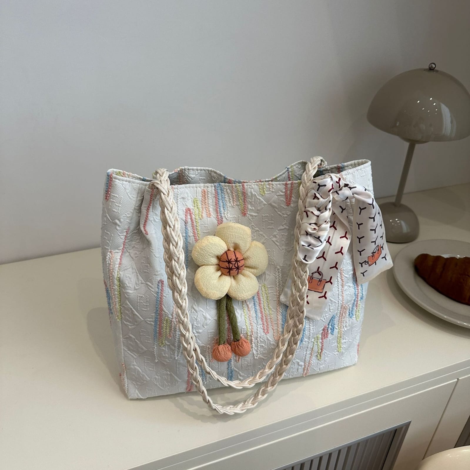 TRENDBUY white floral charm tote bag with braided strap, showcased on a table