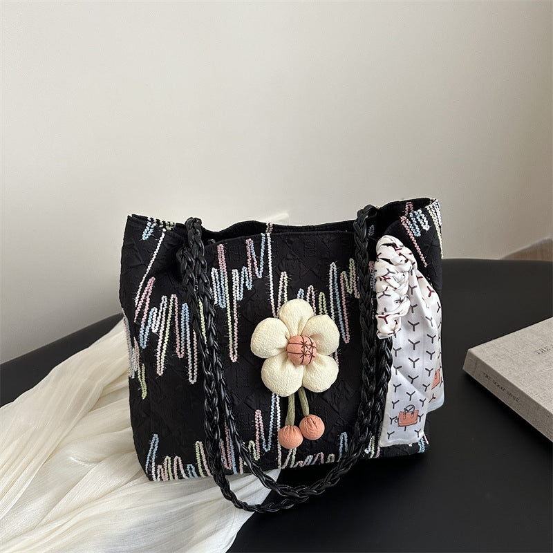 TRENDBUY black floral charm tote bag with braided strap and patterned scarf on a dark surface
